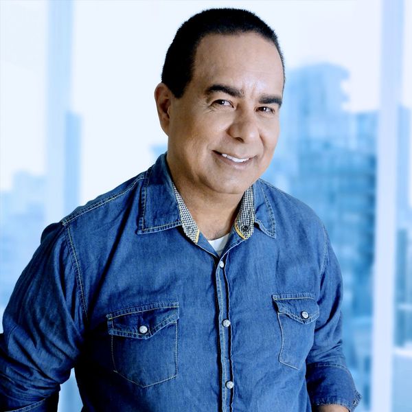 Um homem de camisa jeans está sorrindo para a câmera.