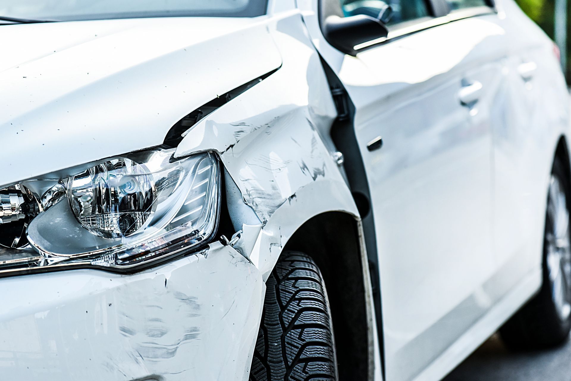 a white car with a damaged fender and headlight