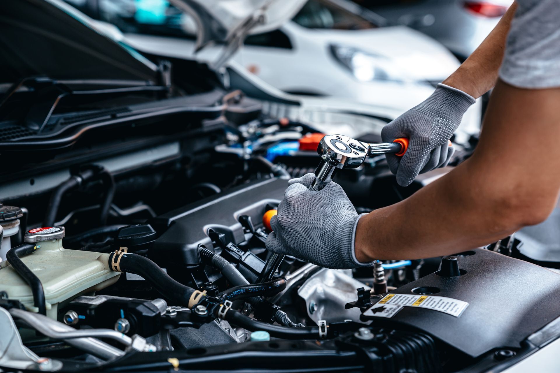 a man wearing gloves is working on the engine of a car