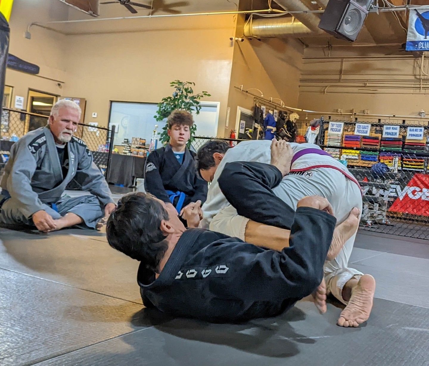 a man and a woman are wrestling on a mat in a gym .