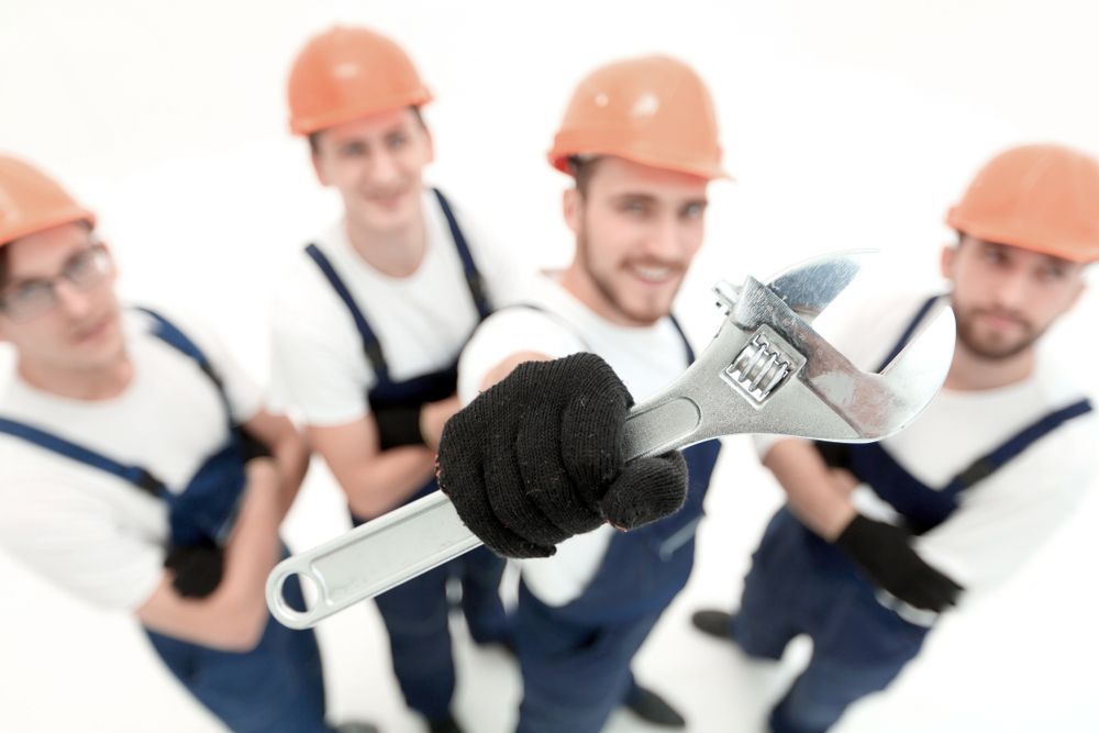 A Group Of Construction Workers Are Holding A Wrench — H2O Plumbing & Maintenance Services In Armidale, NSW