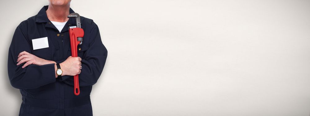 A Man In A Blue Uniform Is Holding A Red Wrench — H2O Plumbing & Maintenance Services In Armidale, NSW