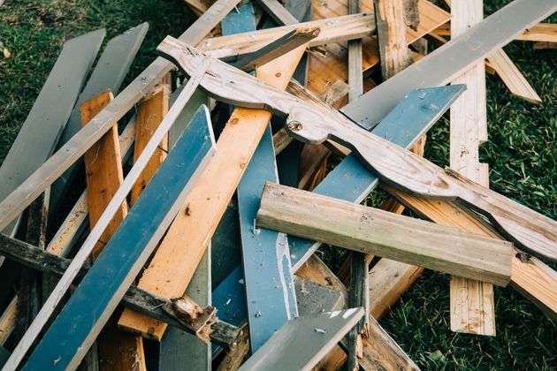 Pile of broken wooden planks and painted boards scattered on grass