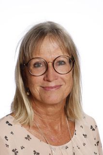 En mand iført briller og jakkesæt smiler til kameraet.