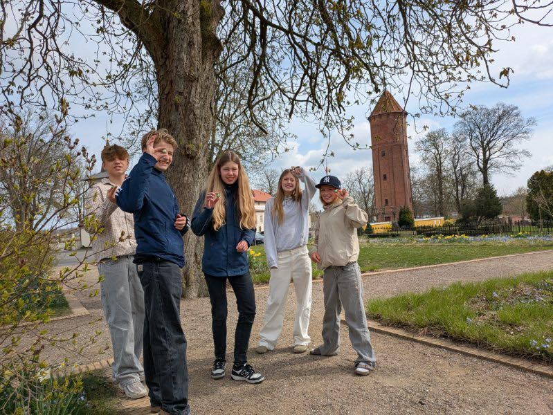 En gruppe unge mennesker poserer til et billede foran et træ.