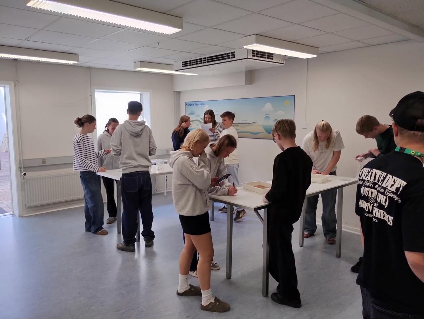 En gruppe mennesker er samlet i et rum, og en af ​​dem har en skjorte på, hvor der står 