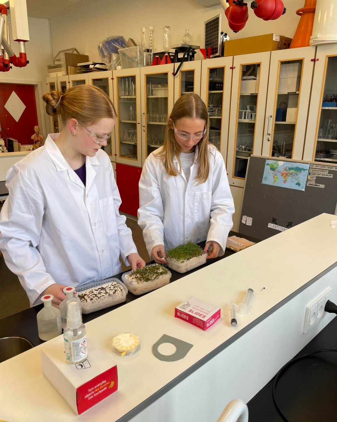 To piger i laboratoriekitler arbejder i et laboratorium.