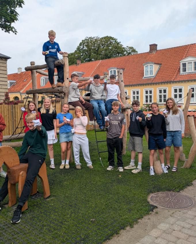 En gruppe unge mennesker poserer til et billede foran et træ.