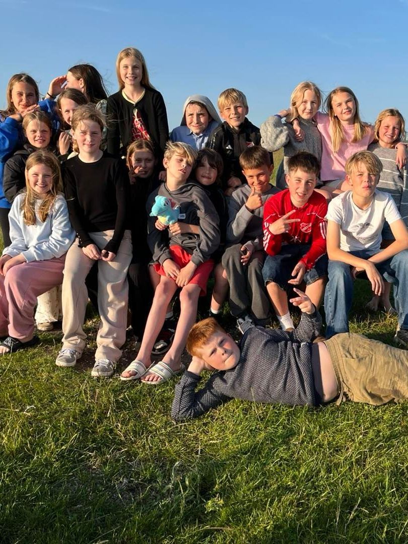 En gruppe børn poserer til et billede i græsset.