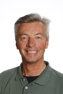 En mand i en grøn skjorte smiler til kameraet.