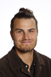 En mand med en knold på hovedet har en brun jakke på.