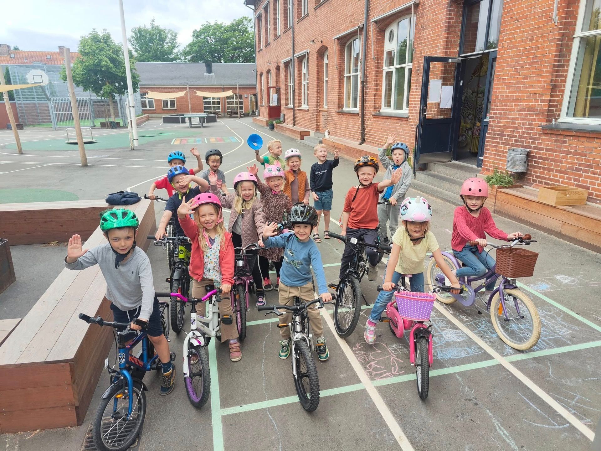En stor gruppe mennesker klædt i kostumer sidder på gulvet i en gymnastiksal.