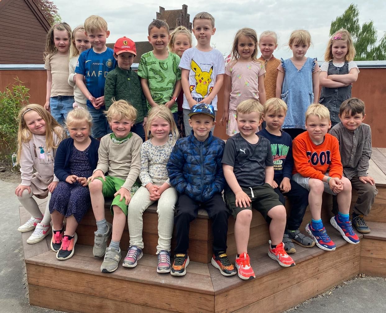 To unge drenge sidder ved et træbord og skriver på et stykke papir.