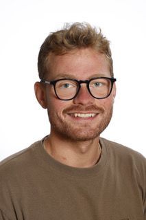 En mand med briller og skæg smiler til kameraet.