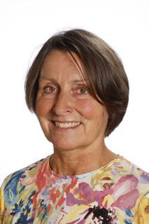 En kvinde i en blomstret skjorte smiler til kameraet.