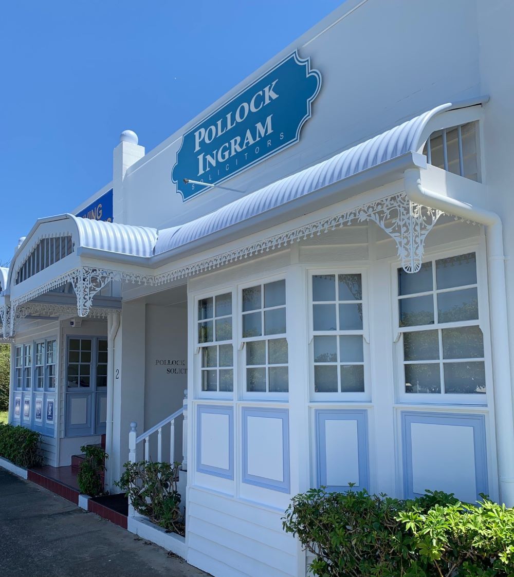 A White Building With a Blue Sign — Pollock Ingram Solicitors in Caloundra, QLD