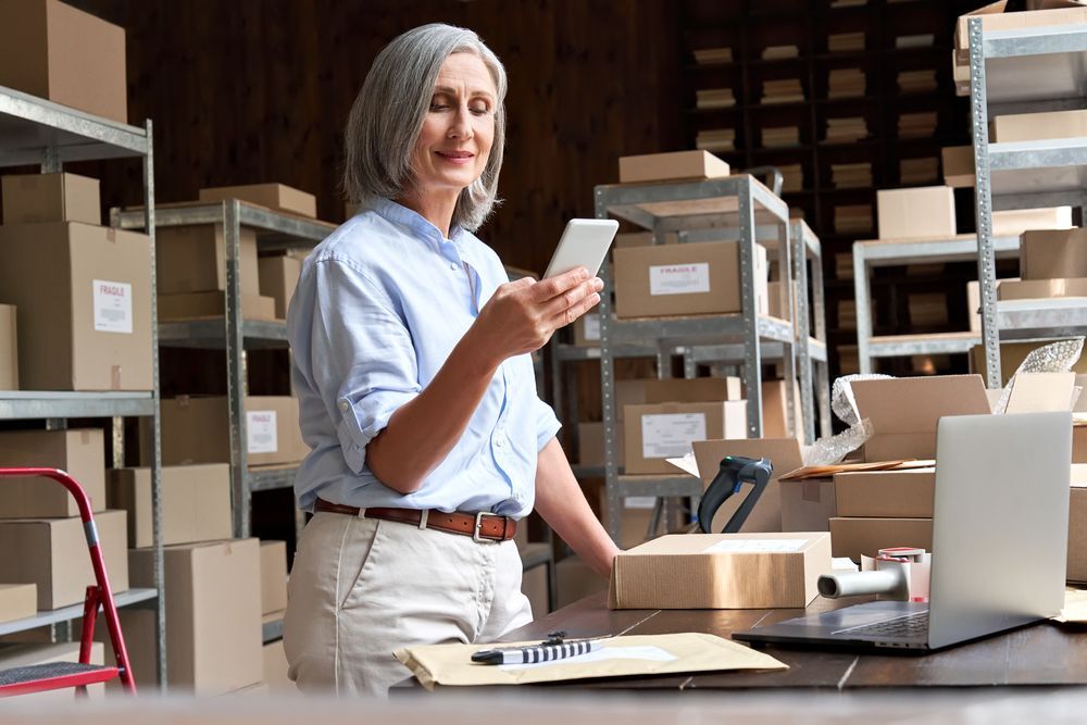 A Woman In A Warehouse Looking At Her Phone — Pollock Ingram Solicitors in Caloundra, QLD