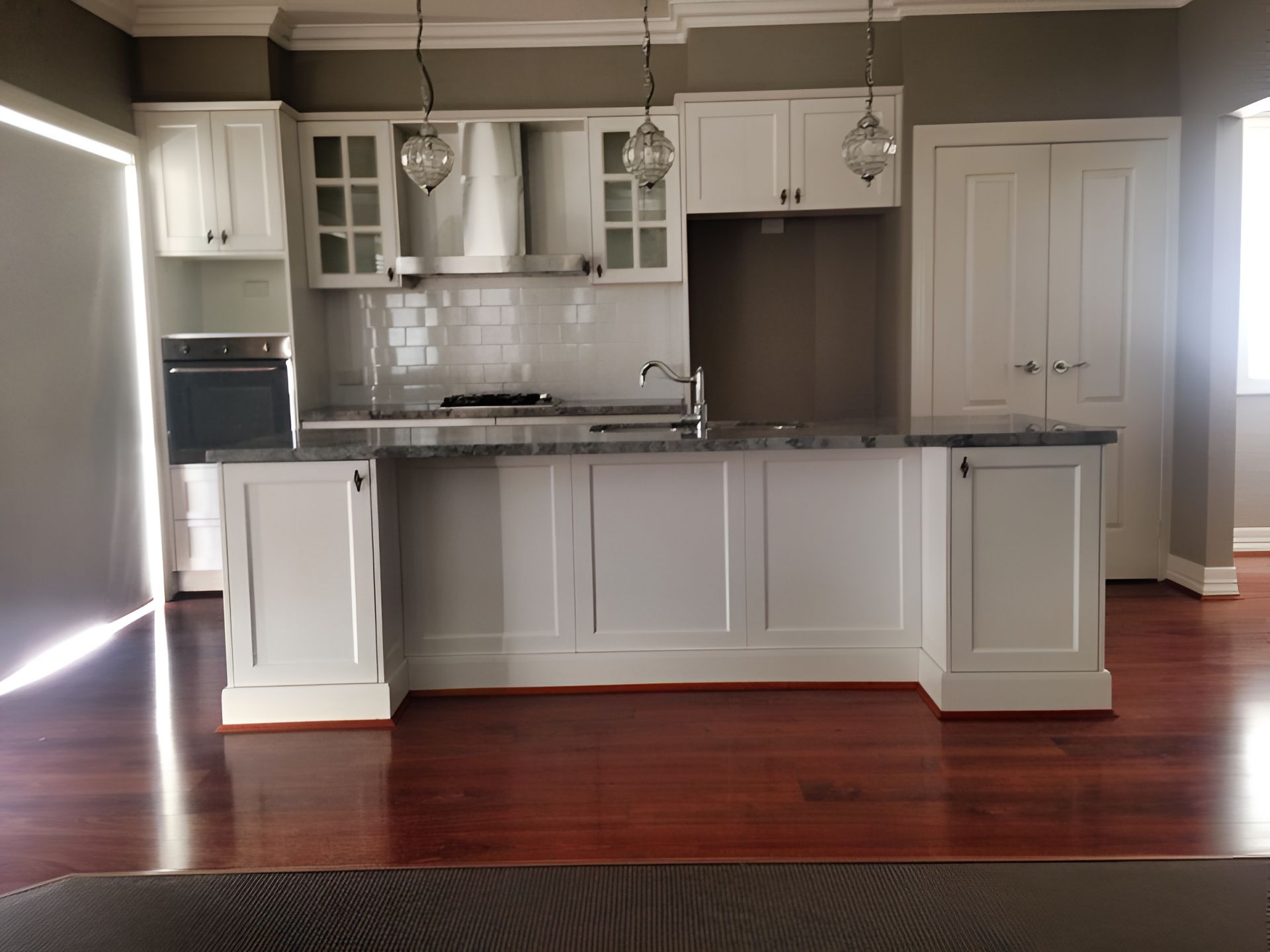 An Empty Kitchen With White Cabinets and Hardwood Floors — Moore Than Just Kitchens In Manilla, NSW