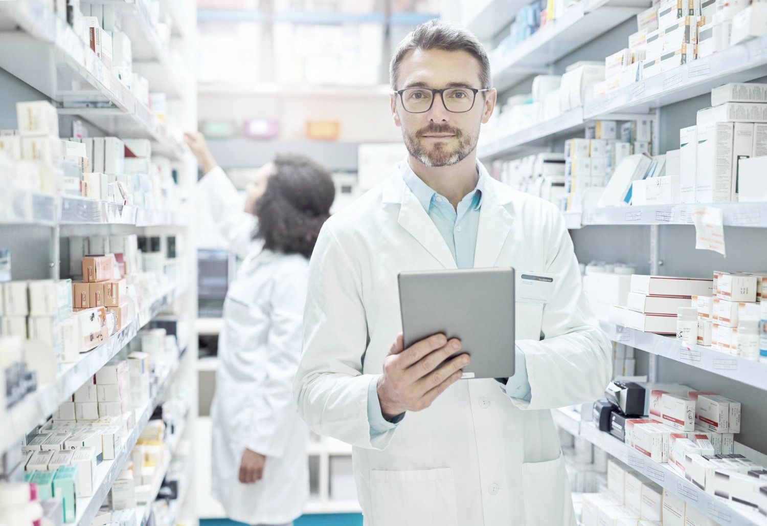 A pharmacist is holding a tablet in a mail-order pharmacy fulfillment center.
