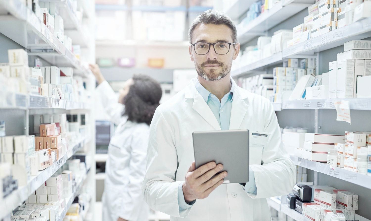 A pharmacist is holding a tablet in a mail-order pharmacy fulfillment center.