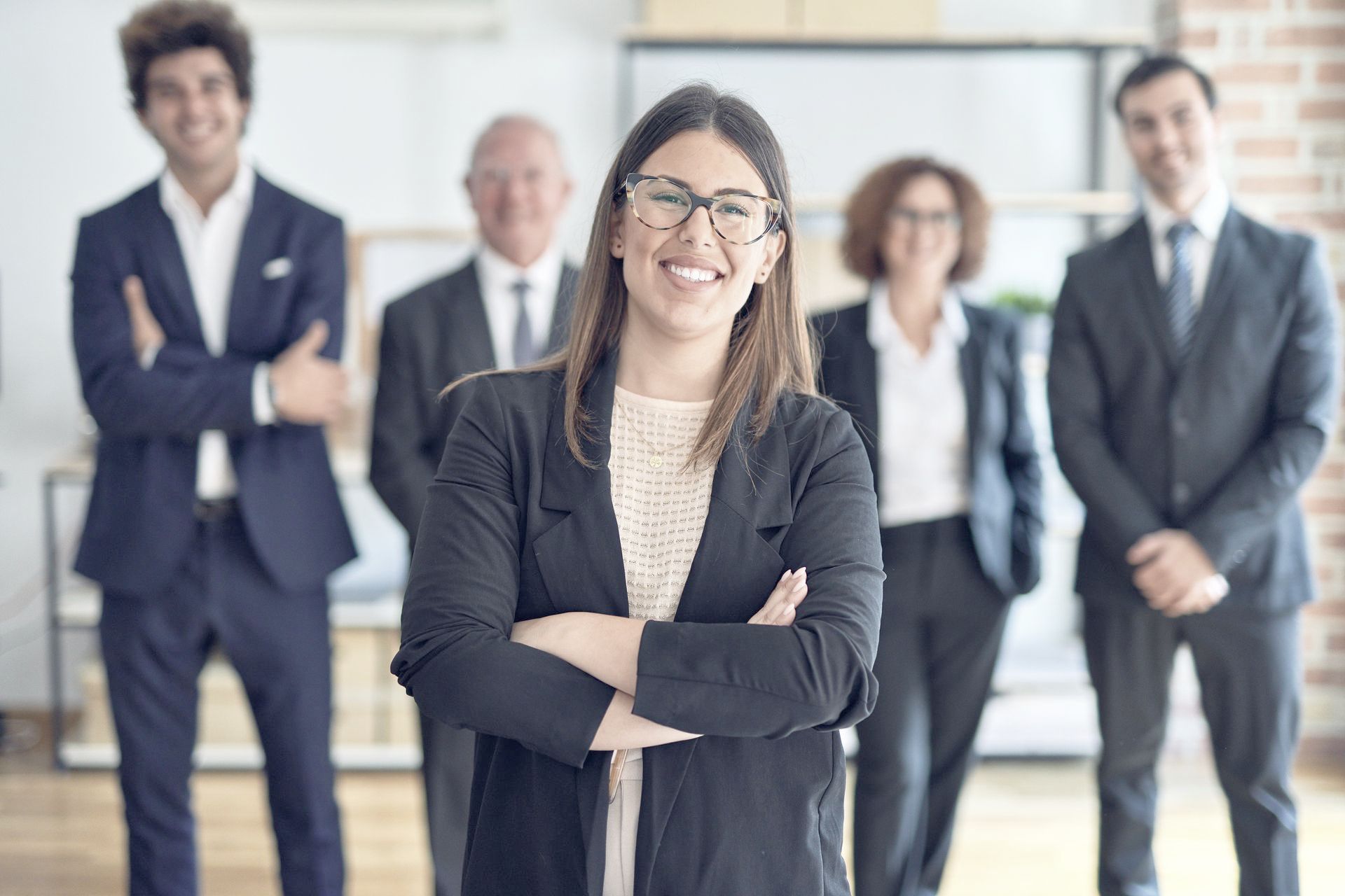 A smiling woman is standing in front of a group of happy business people.