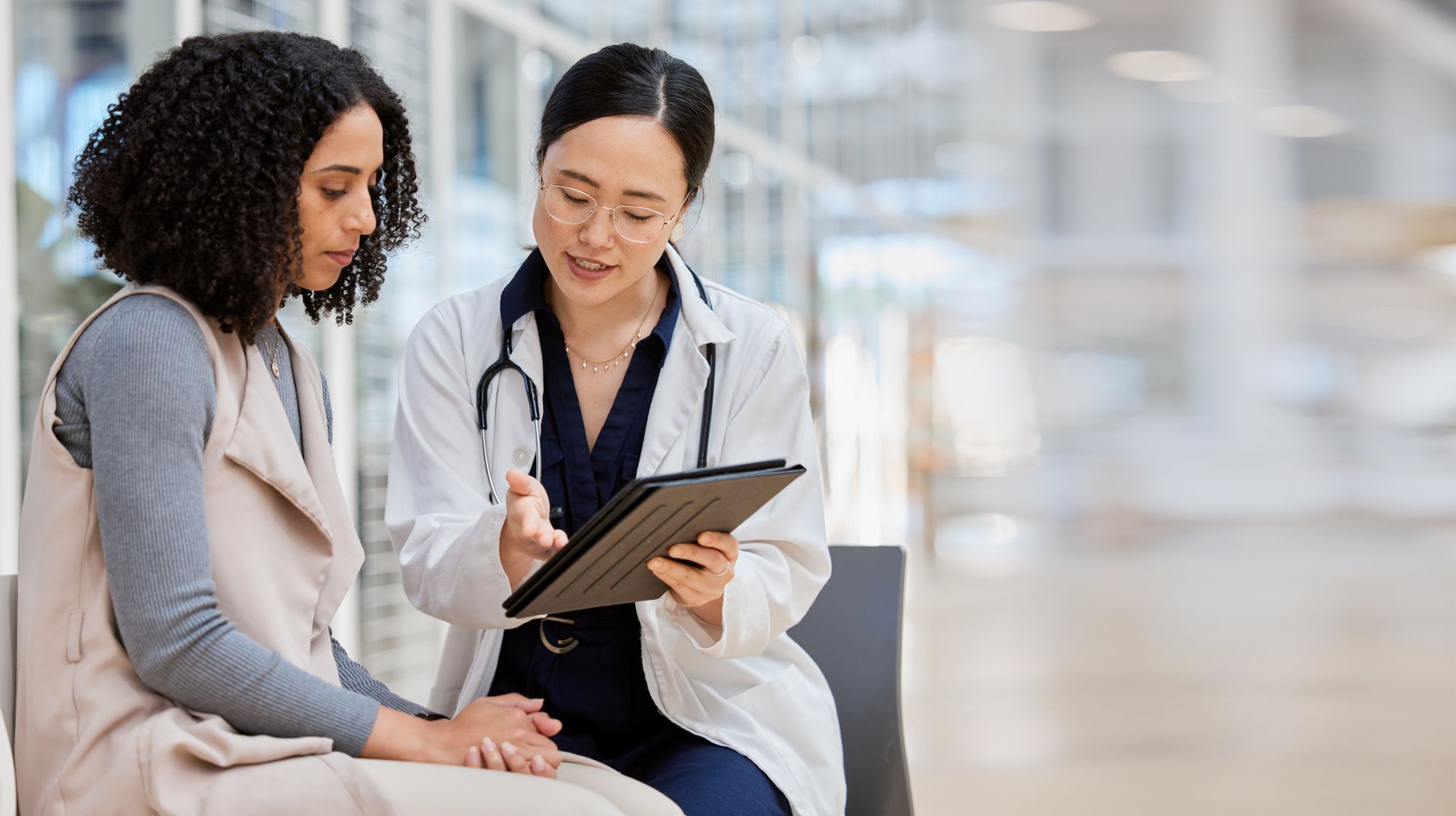 A doctor reviews information on a tablet with a patient in a medical facility.