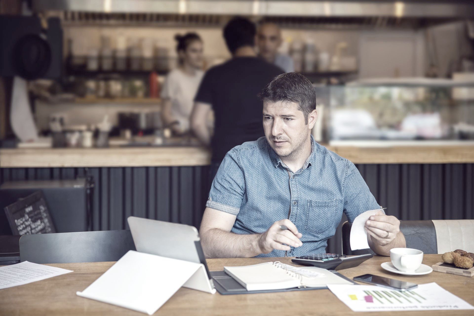 a man is sitting at a table in a restaurant looking at his small business budget