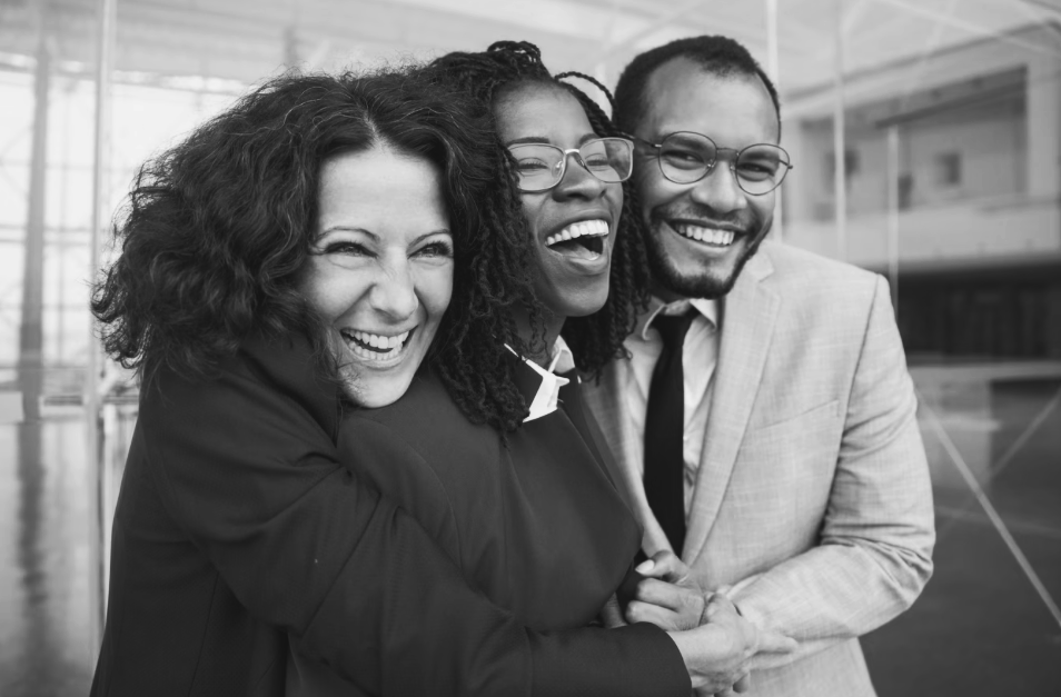 A man and two women are hugging each other in a black and white photo.