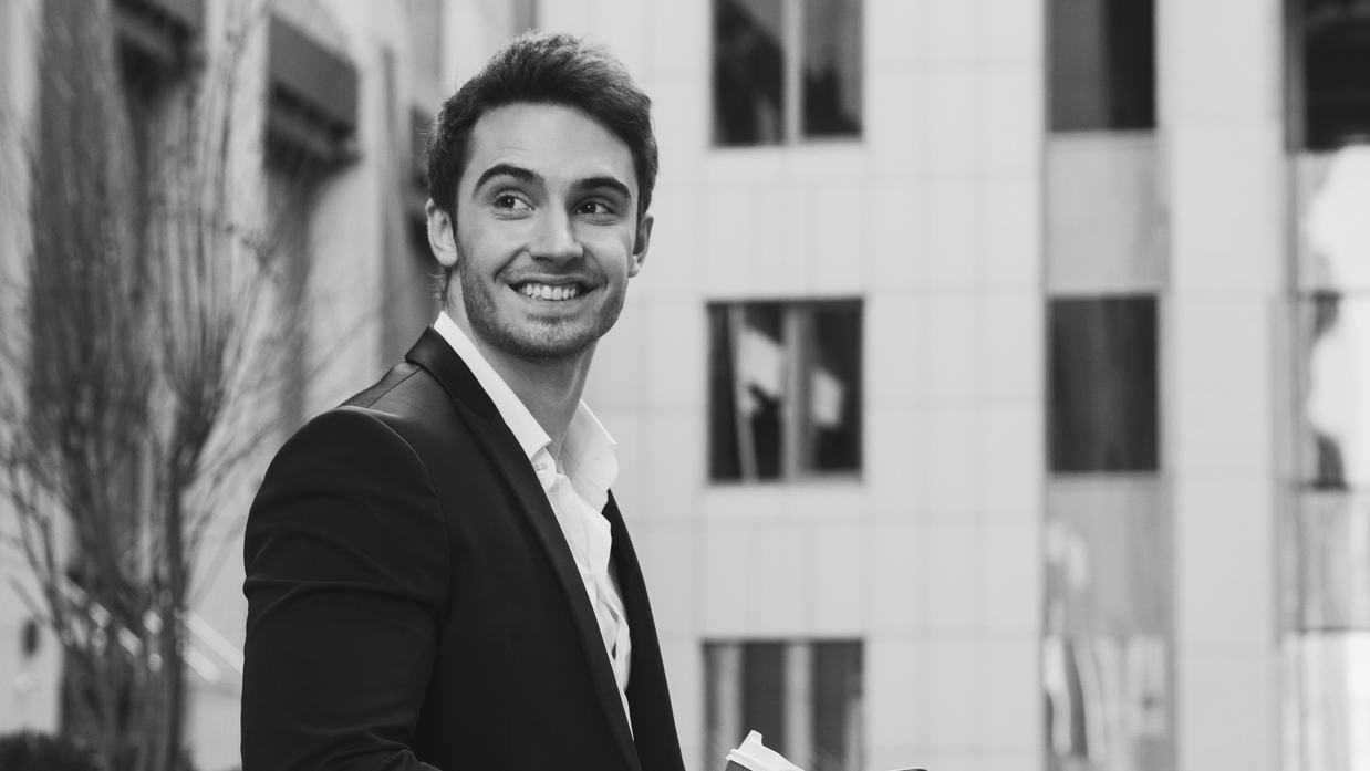 a man in a suit is smiling in front of a building