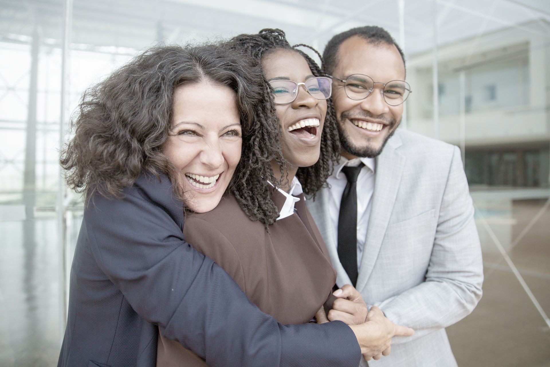 A man and two women are hugging each other and smiling.