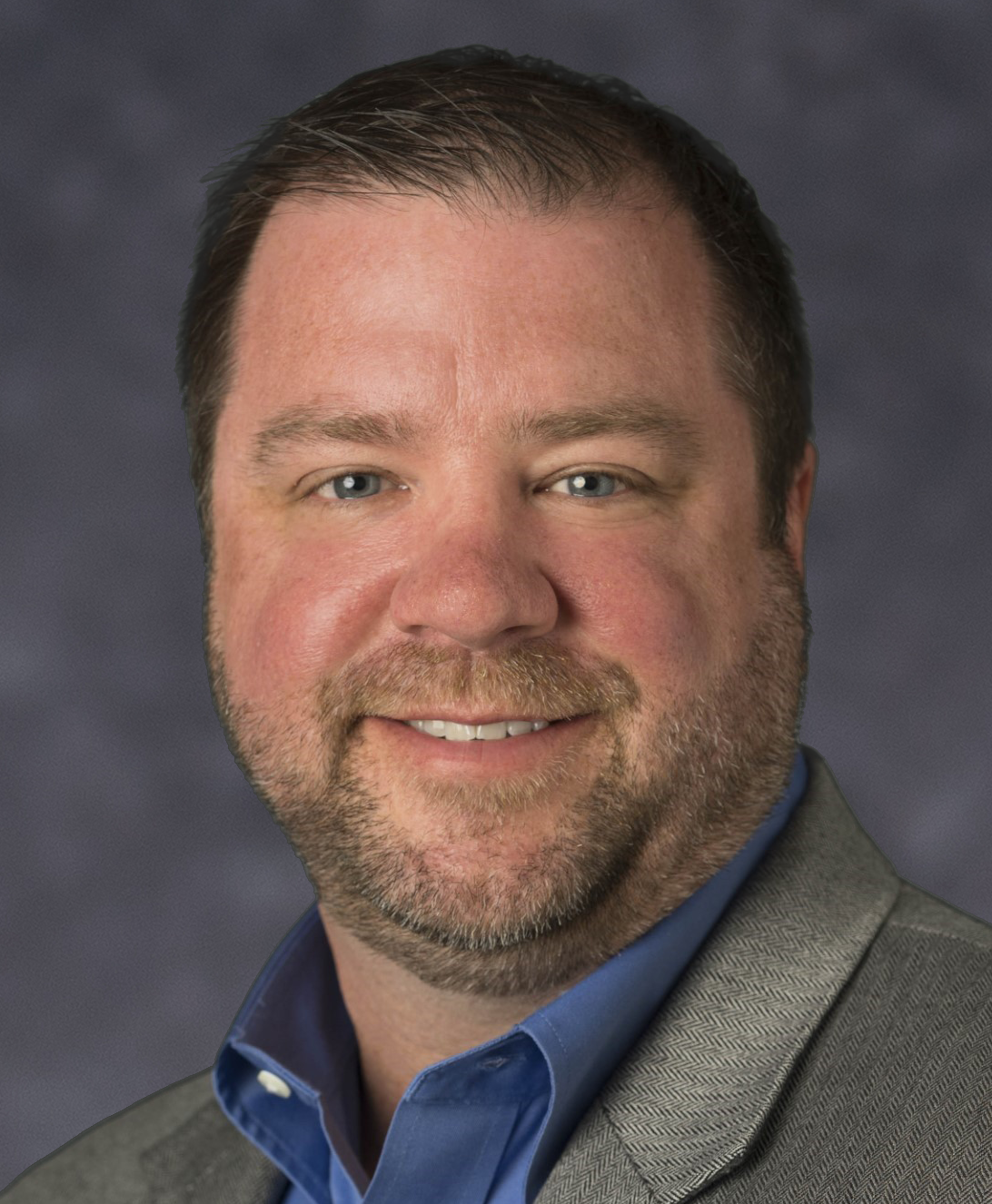 A man in a suit and blue shirt is smiling for the camera.