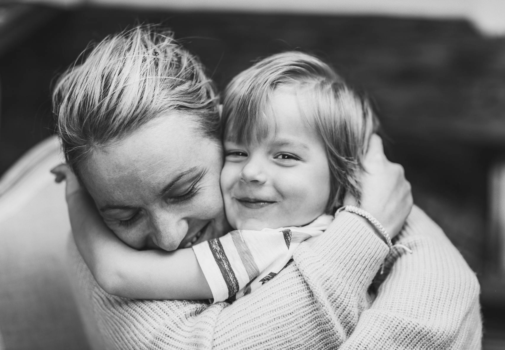 A woman is hugging a little boy in a black and white photo.