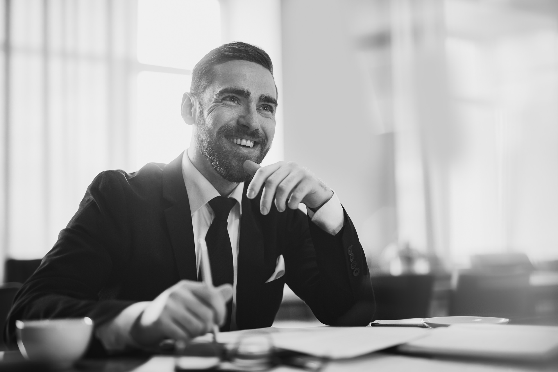 A black and white photo of a man in a suit and tie sitting at a table.