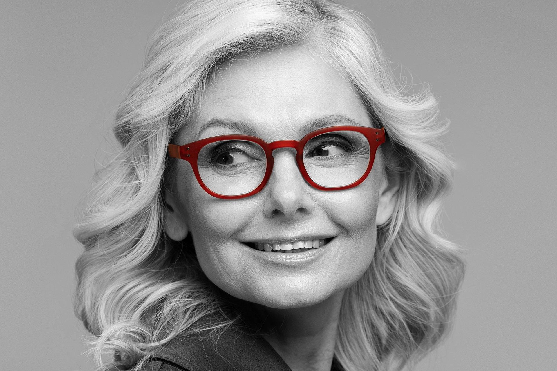 a woman wearing red glasses is smiling in a black and white photo