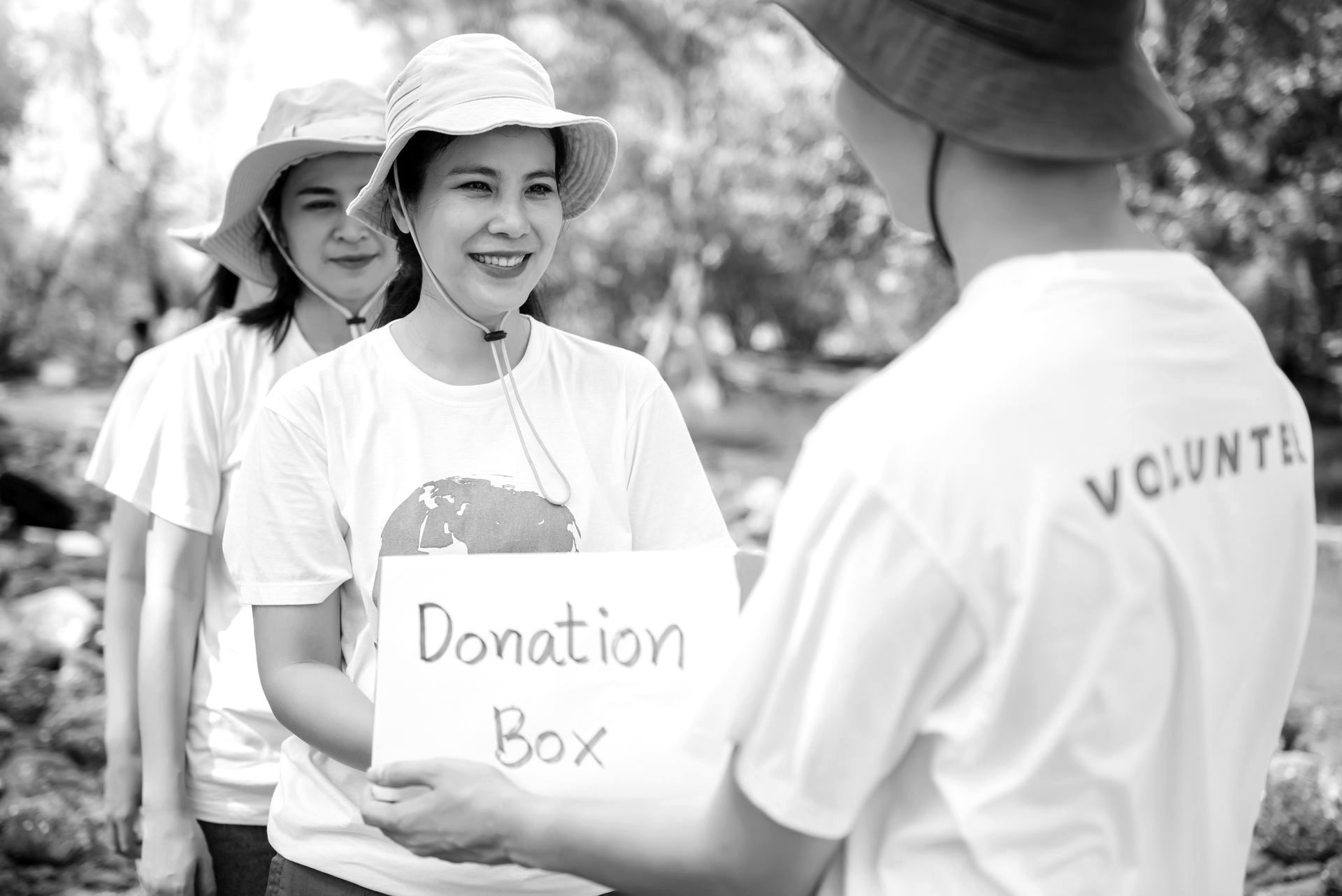 A group of volunteers are holding a sign that says `` donation box ''.