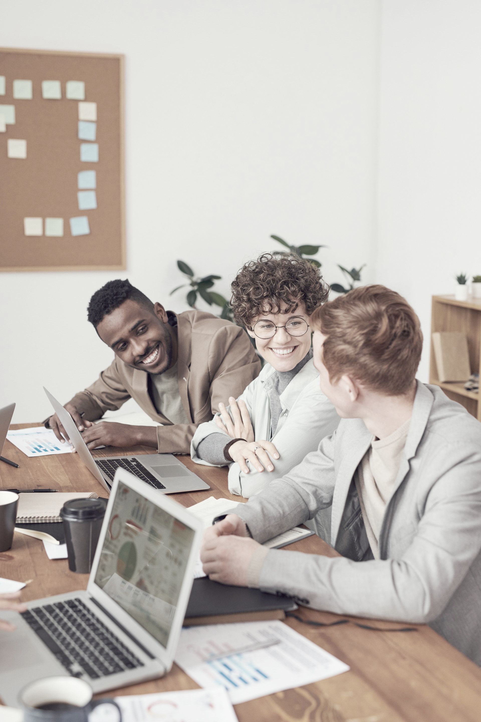 A group of people are sitting around a table with laptops.