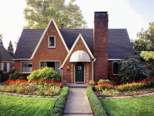 A brick house with a black roof and a green door