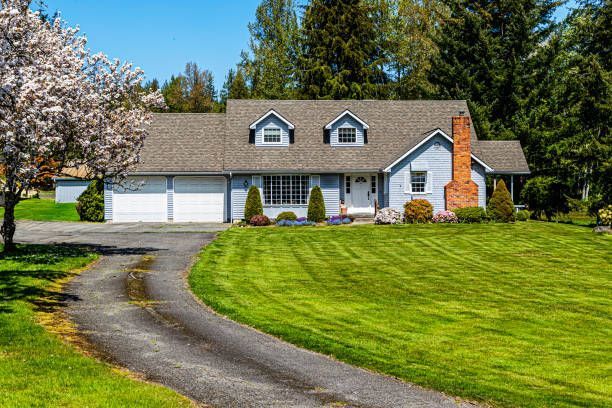 A house with a lush green lawn and a driveway leading to it.