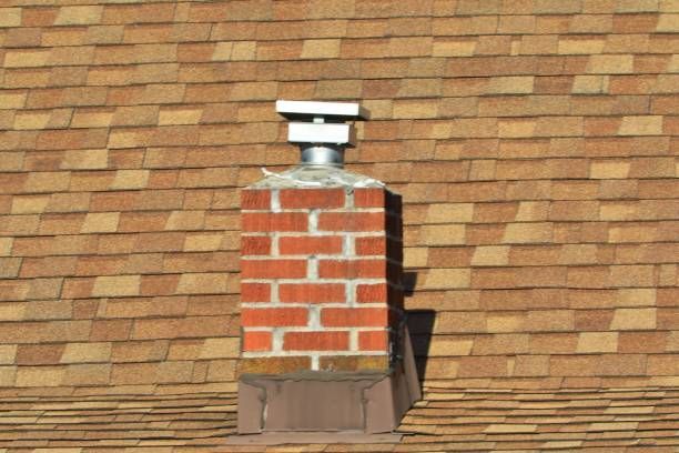 A brick chimney on top of a roof with shingles
