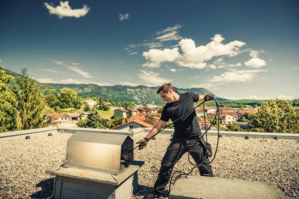 A man is working on a chimney on the roof of a building.