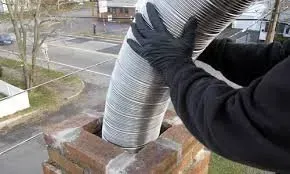 A person is fixing a chimney with a flexible hose.