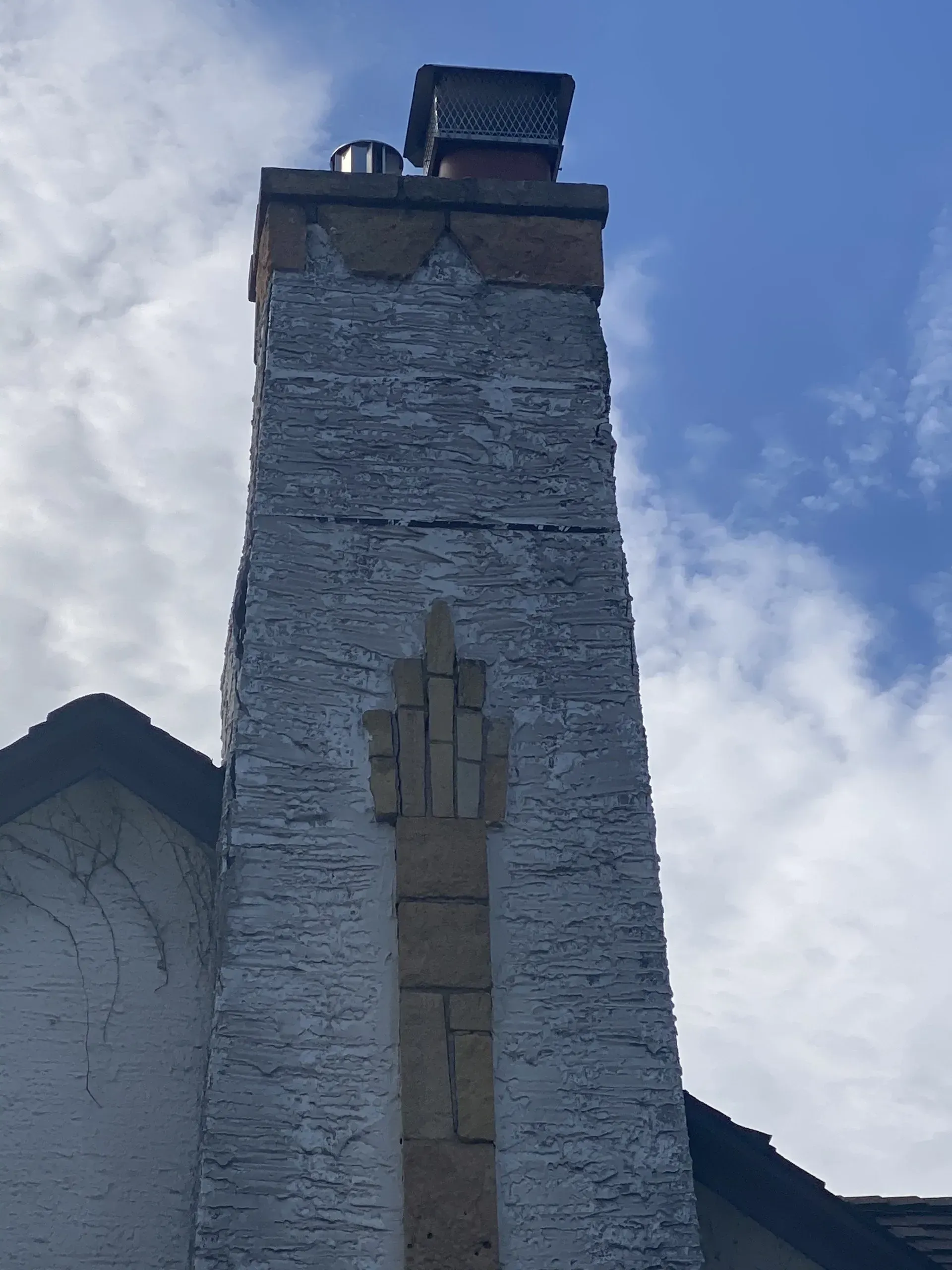 A chimney on the side of a building with a blue sky in the background