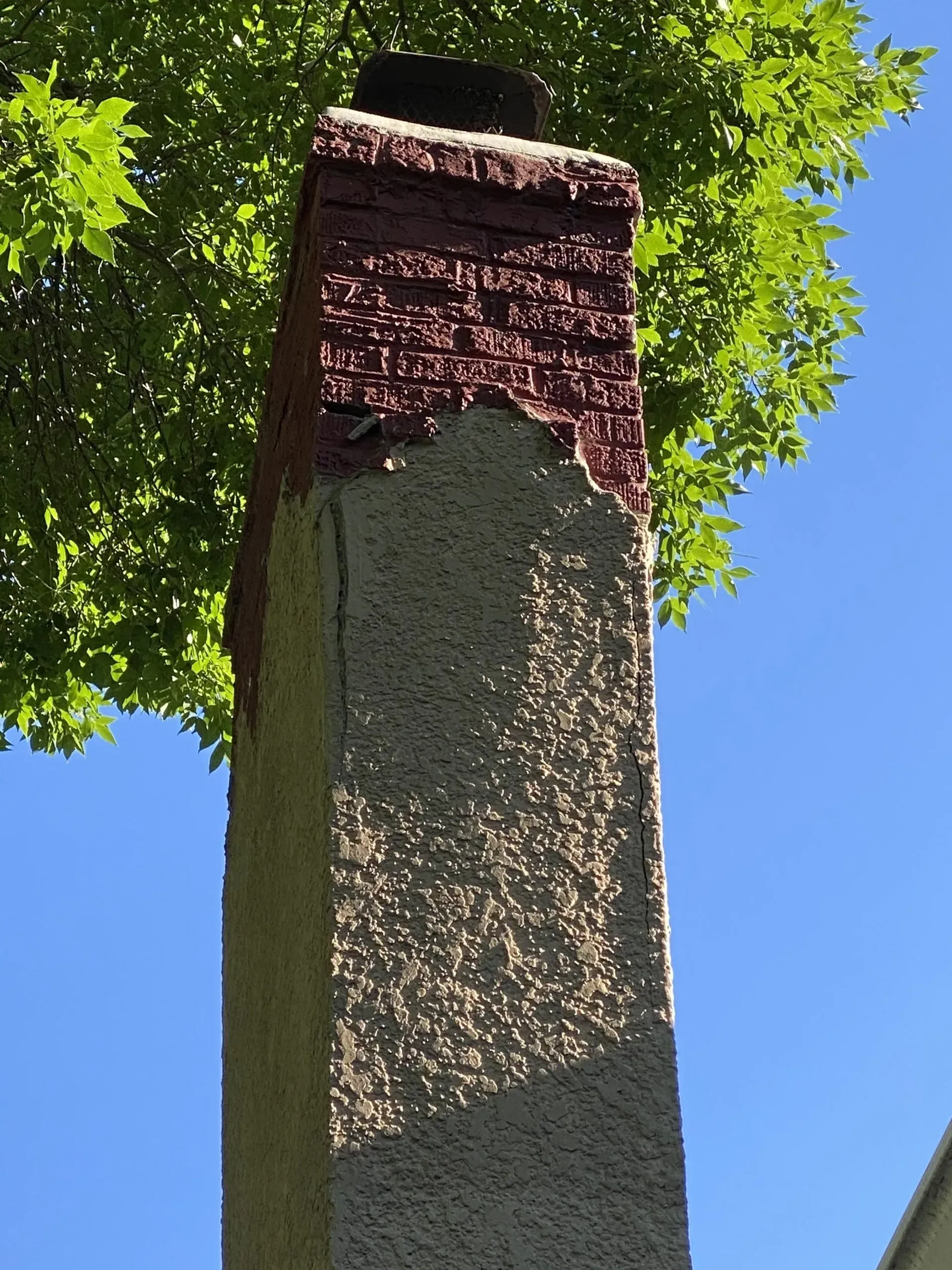 A chimney with a tree in the background and a blue sky