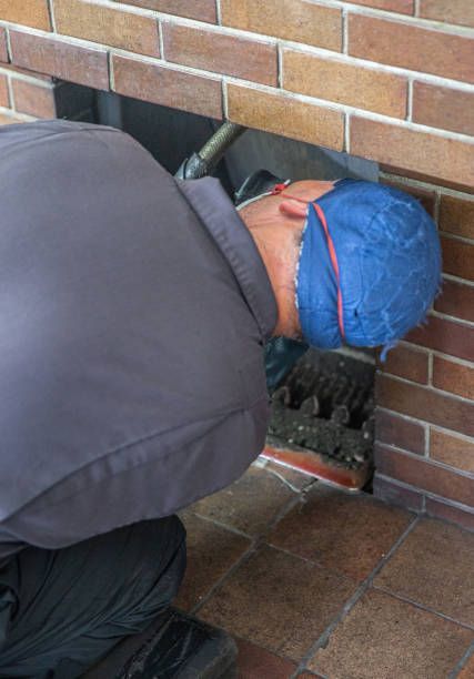 A man wearing a blue hat and goggles is working on a brick wall.