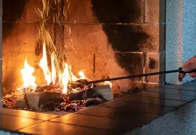 A person is lighting a fireplace with a lighter.