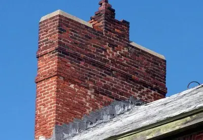 A brick chimney on top of a building with a blue sky in the background.