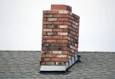 A brick chimney is sitting on top of a roof.