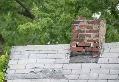 A brick chimney is sitting on top of a roof.