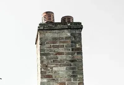 A brick chimney with two chimneys on top of it.