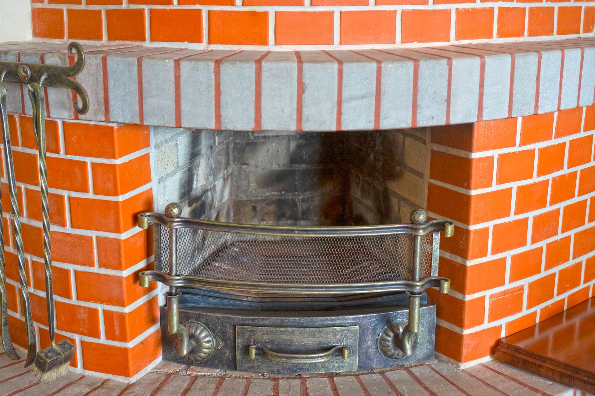 A red brick fireplace with a metal grate on the bottom of it.